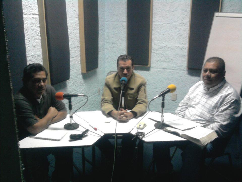 Tres participantes frente a micrófonos durante una charla dominical en cabina
